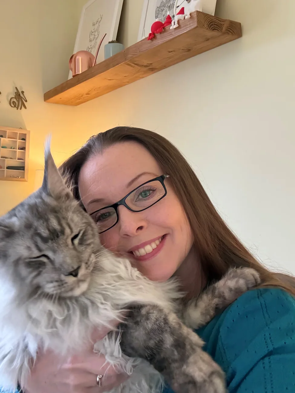 Jenn from The Cotswold Cat Sitters cuddling a grey long-haired cat